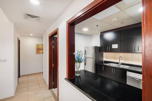 - une cuisine avec des comptoirs noirs et un réfrigérateur dans l'établissement Sunkissed holiday homes 2-3BR Apartments on JBR beach near mall & metro & bluewaters Island, à Dubaï