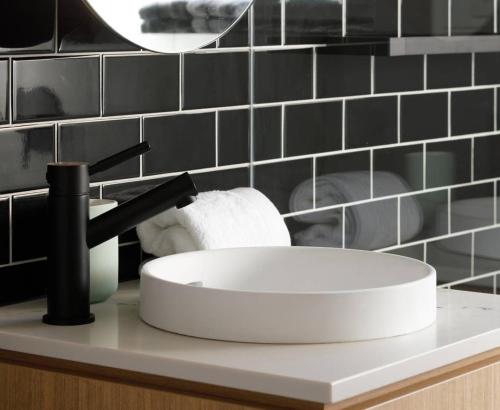a white sink in a bathroom with black tiles at 2 Bdrm Apt in Annandale with Courtyard & Parking in Sydney
