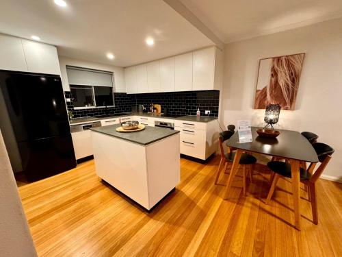 a kitchen with a black refrigerator and a table at 2 Bdrm Apt in Annandale with Courtyard & Parking in Sydney
