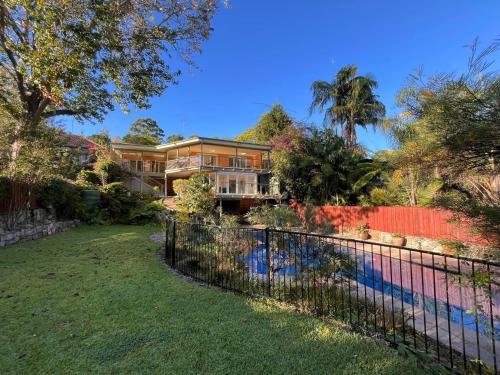 a house with a fence in front of a yard at Poolside oasis - Sydney in Sydney