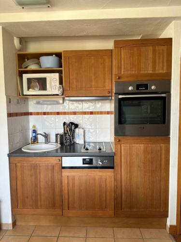 a kitchen with wooden cabinets and a sink and a microwave at STUDIO Perce Neige Lagrange in Saint-Lary-Soulan