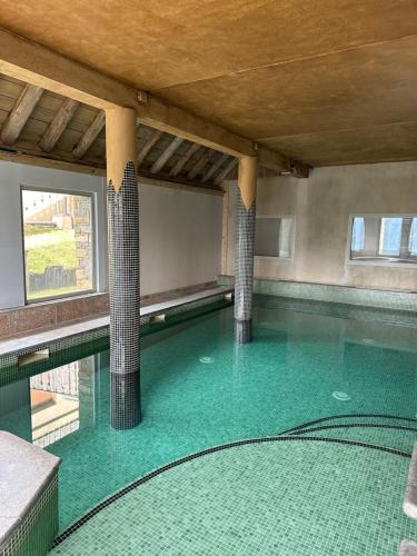 a swimming pool with two columns and green water at STUDIO Perce Neige Lagrange in Saint-Lary-Soulan
