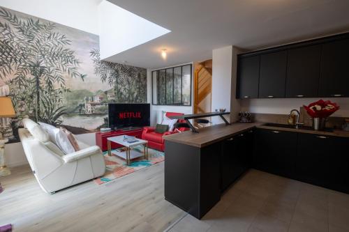 une cuisine avec des armoires noires et un salon dans l'établissement DUPLEX Complet - PROCHE DYSNEY LAND PARIS, à Bussy-Saint-Georges