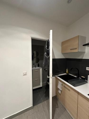 - une cuisine avec un évier et une porte ouverte dans l'établissement Charmant studio, à La Colle-sur-Loup