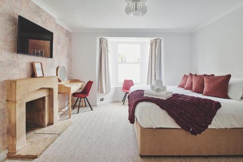 a bedroom with a bed with a fireplace and a desk at The Lansdowne Boutique Rooms with Breakfast - Adults Only in Bourton on the Water