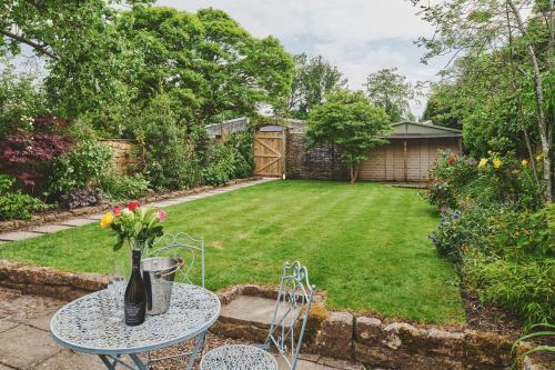a garden with a table with a vase of flowers on it at The Lansdowne Boutique Rooms with Breakfast - Adults Only in Bourton on the Water