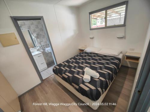 małą sypialnię z łóżkiem i lustrem w obiekcie Wagga Wagga Tourist Park w mieście Wagga Wagga