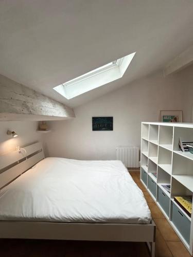 - une chambre avec un grand lit blanc et une lucarne dans l'établissement Le Blum Arles centre, à Arles