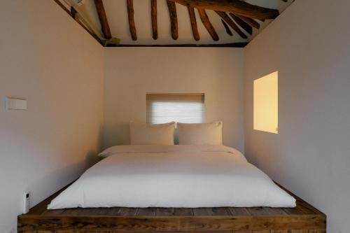 a bed with white sheets and pillows in a room at Stay kkachi #center of Hanok village in Jeonju