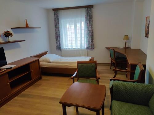 a room with a bed and a desk and chairs at Gästehaus Einzinger in Krems an der Donau
