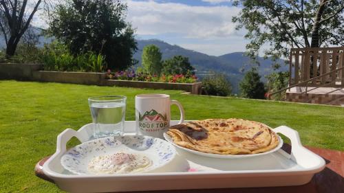 una bandeja con un plato de comida y un vaso de agua en Roof Top Resort, en Murree
