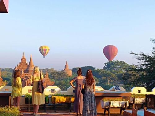 un grupo de mujeres de pie delante de algunos globos de aire caliente en Myanmar Nan Hteik Temple View Hotel, en Bagan