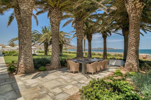 a patio with a table and chairs under palm trees at Villa Bellonia in Naousa