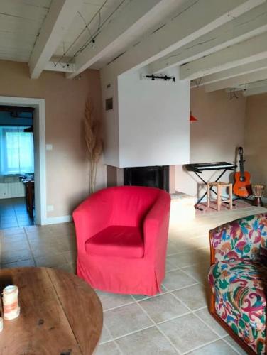 a living room with a red chair and a table at Gîte au gré du vent in La Goutelle
