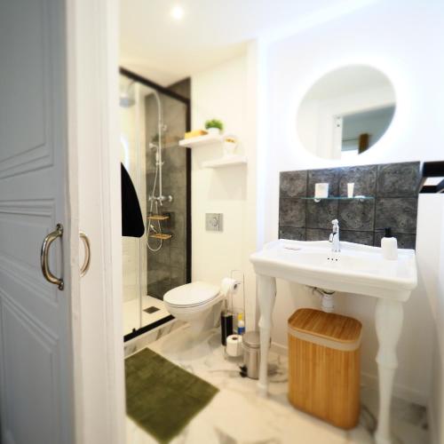 une salle de bain avec un lavabo et des toilettes dans l'établissement Les Ambassadeurs quartier Opéra, à Vichy