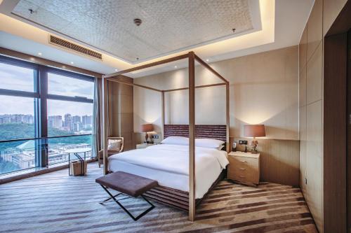 貴陽市にあるRenaissance Guiyang Hotelのベッドと大きな窓が備わるホテルルームです。