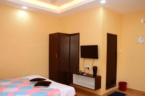 a bedroom with a bed and a dresser with a television at sivashankaran homes in Tiruvannāmalai