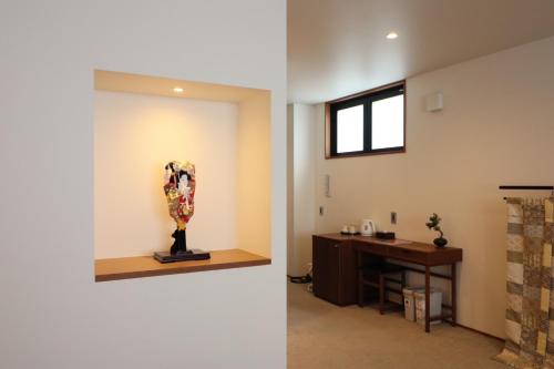 a room with a desk and a statue next to a wall at Hotel Rakurakuan in Kyoto