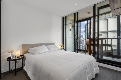 a bedroom with a white bed and a large window at City High-Rise 1-Bed with Pool, Gym and Parking in Brisbane