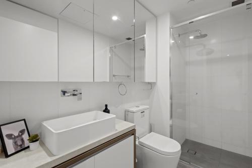 a white bathroom with a sink and a toilet at City High-Rise 1-Bed with Pool, Gym and Parking in Brisbane