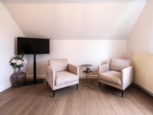 a living room with two chairs and a tv at Maison Idyllique in Bree