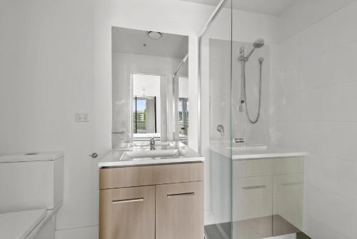 a white bathroom with a sink and a shower at Sleek City Apartment with Parking and Balcony in Brisbane