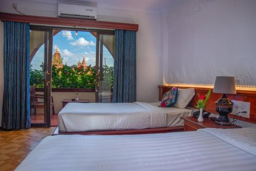 Habitación de hotel con 2 camas y ventana grande. en Myanmar Nan Hteik Temple View Hotel en Bagan