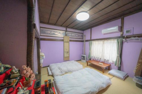 1 dormitorio con paredes de color púrpura, 1 cama y 1 mesa en 小樽民泊太田1号館, en Otaru