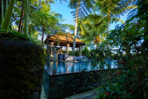 a pool with an elephant in the middle of a resort at Prabhu Ubud Villa in Ubud