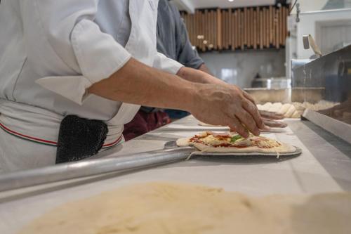 a man making a pizza on a counter in a kitchen at Caretta Paradise Resort & WaterPark in Tragaki