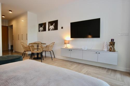 a bedroom with a tv on the wall and a table at Apartamenty Solaris in Darłówko