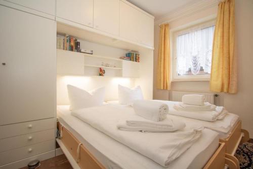 sypialnia z łóżkiem z białą pościelą i ręcznikami w obiekcie Hebben-Exclusives-Urlaubsdomizil-direkt-am-Strand w mieście Westerland