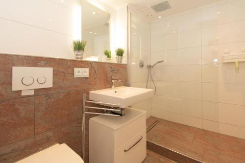 W łazience znajduje się umywalka, toaleta i lustro. w obiekcie Hebben-Exclusives-Urlaubsdomizil-direkt-am-Strand w mieście Westerland