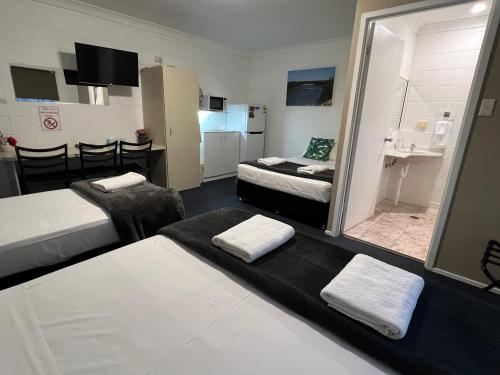 a room with two beds and a bathroom with a sink at Spanish Lace Motor Inn in Townsville