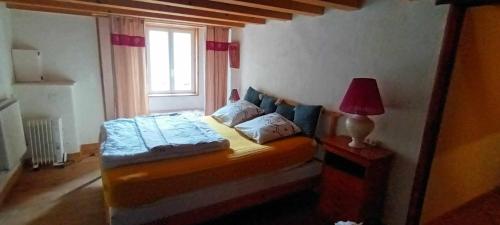 ein Schlafzimmer mit einem Bett mit einer Lampe und einem Fenster in der Unterkunft maison du 13eme siècles in La Genétouze
