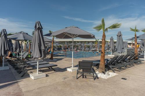 a group of chairs and umbrellas next to a pool at Caretta Paradise Resort & WaterPark in Tragaki