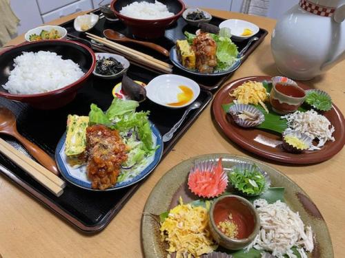 una mesa con platos de comida y cuencos de arroz en Kami House, en Amami