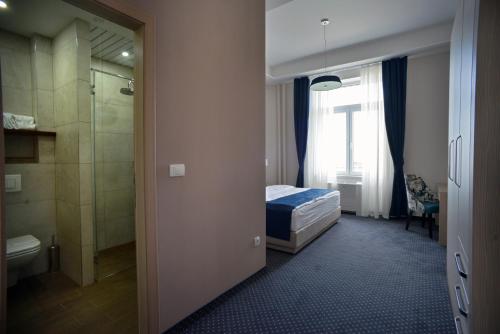 a bedroom with a bed and a bathroom with a shower at Five Points Square - City Center in Belgrade