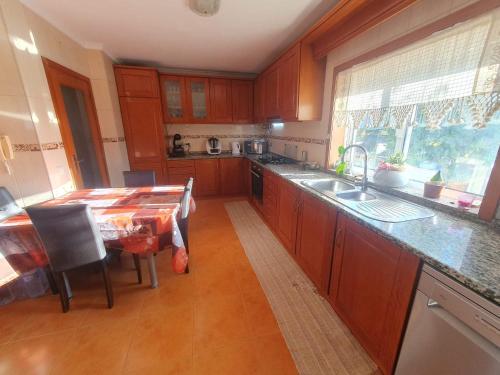 a kitchen with wooden cabinets and a table with a sink at Grace House in Belinho