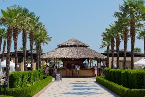 a restaurant with palm trees in front of a building at DIT Majestic Beach Resort - Ultra All Inclusive in Sunny Beach