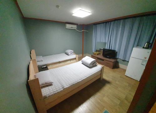 - une petite chambre avec 2 lits et un réfrigérateur dans l'établissement Green Valley, à Sancheong