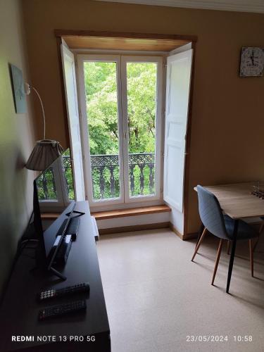 une pièce avec un bureau et une grande fenêtre dans l'établissement location appartement T1 hyper centre 350 m des thermes 200 m des télécabines deuxième étage avec ascenseur, à Luchon