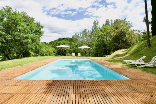 a swimming pool with a wooden floor and a table at Beautiful country house in the heart of Tuscany in Capolona