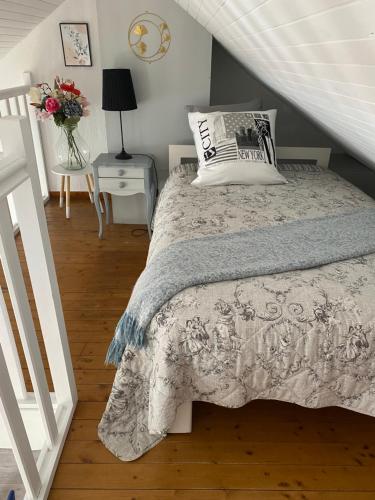 Un dormitorio con una cama y una mesa con un jarrón de flores en La Belle symphonie en Vieil-Moutier