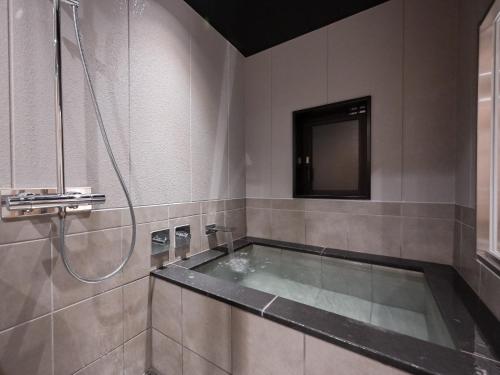 a bathroom with a tub with a shower and a television at Ureshino Onsen Yadoya Uchiroji in Ureshino