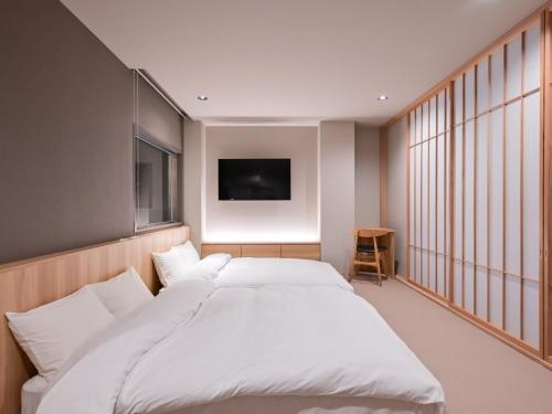 a bedroom with a large white bed and a television at Ureshino Onsen Yadoya Uchiroji in Ureshino