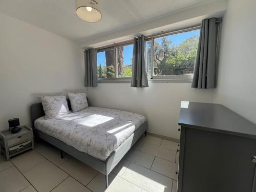 une chambre avec un lit et deux fenêtres dans l'établissement Au cœur des vacances, à Bandol