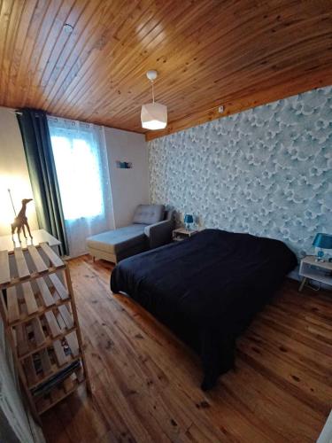 - une chambre avec un lit noir et un canapé dans l'établissement Logis des Pivoines, à Trézelles
