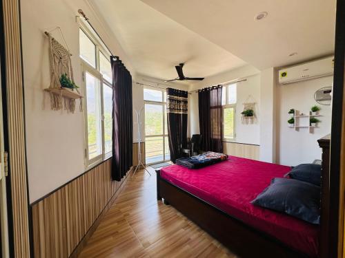 ein Schlafzimmer mit einem roten Bett in einem Zimmer mit Fenstern in der Unterkunft Dhauladhar Homes in Dharamshala