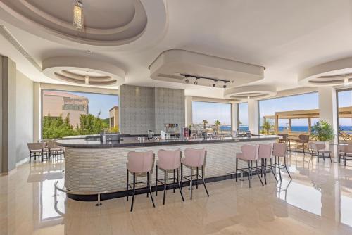 a lobby with a bar with pink stools at KRESTEN ROYAL Euphoria Resort in Kallithea Rhodes